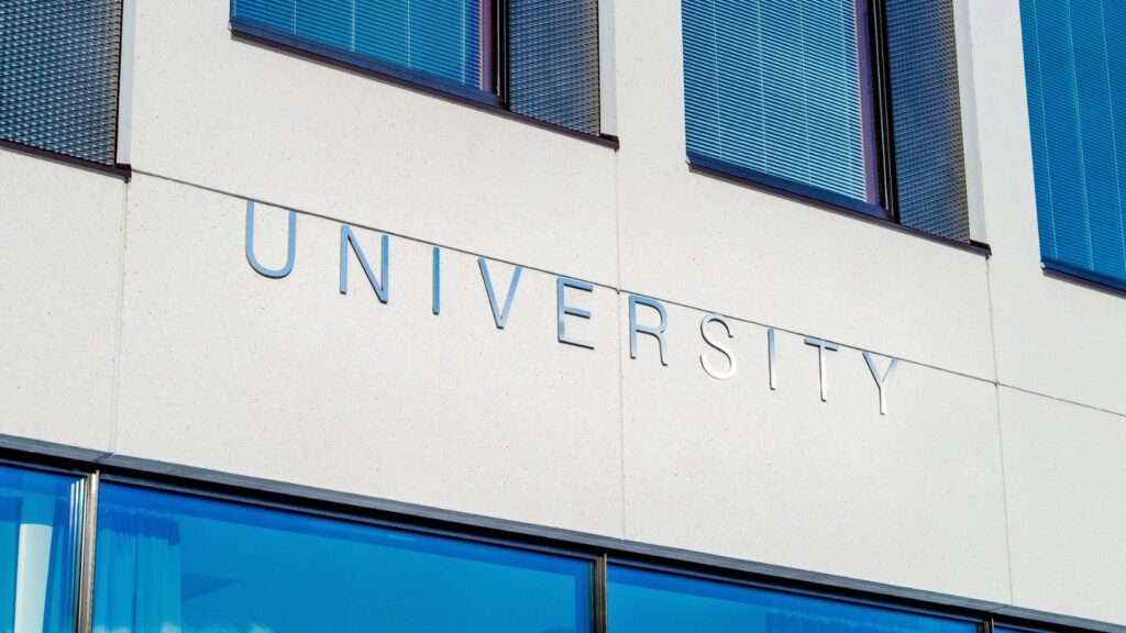 Detail of concrete building with windows. The word "UNIVERSITY" is affixed to the building exterior.